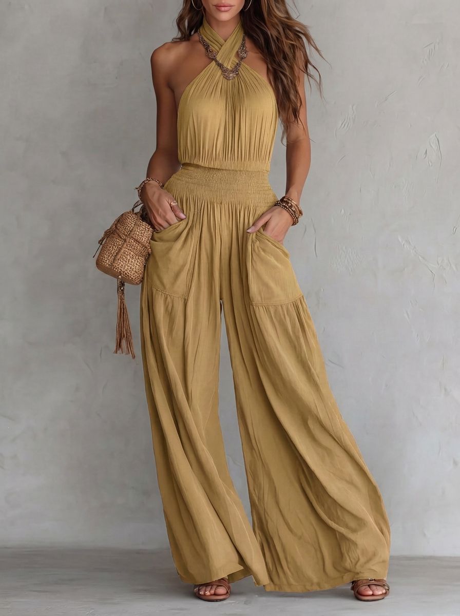 Mustard bohemian halter jumpsuit with wide legs, large pockets, and drawstring waist. Sleeveless backless design.